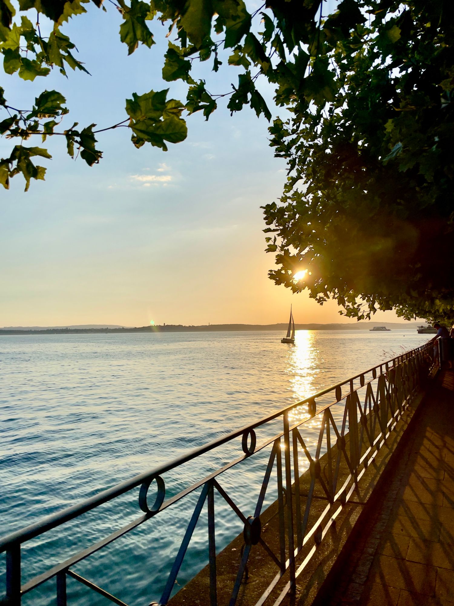 Abendstimmung an der Uferpromenade von Meersburg mit Segelboot auf dem Bodensee